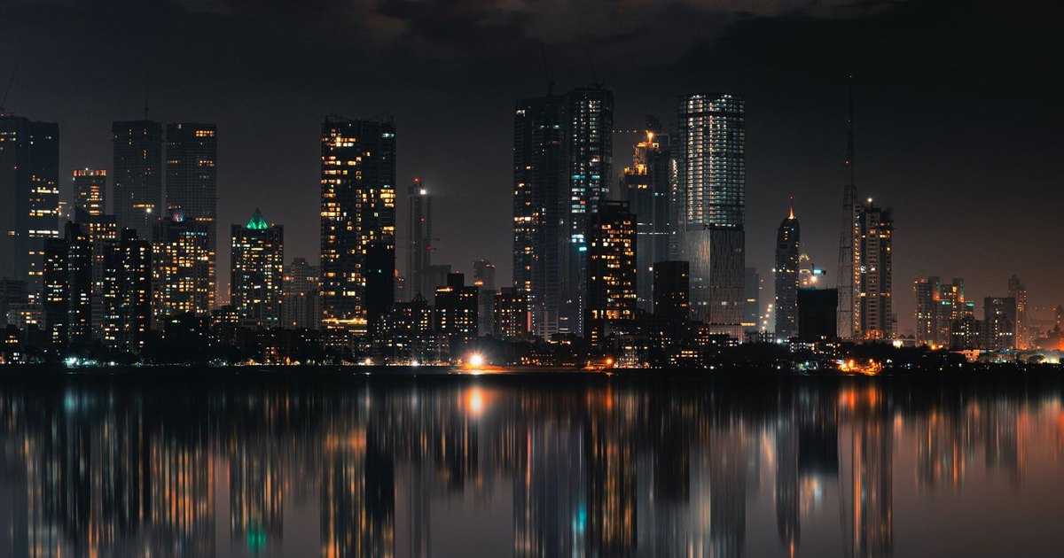 Captivating night view of Mumbai skyline with skyscrapers and reflections on still water.