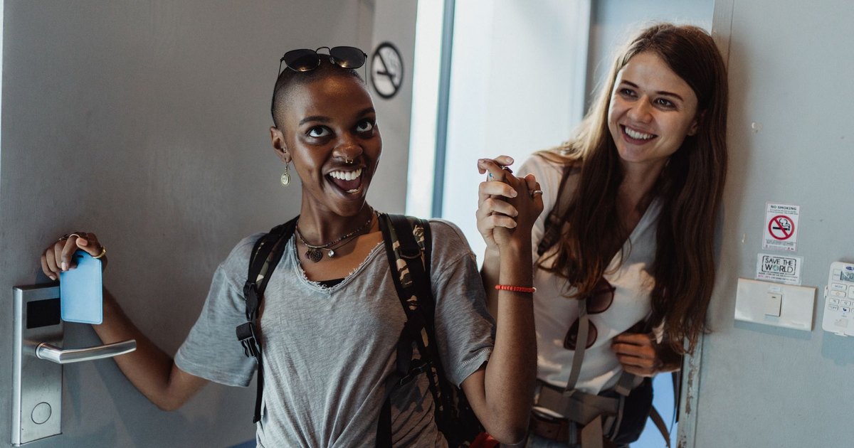 Two cheerful women entering a modern room, capturing moments of fun and friendship.
