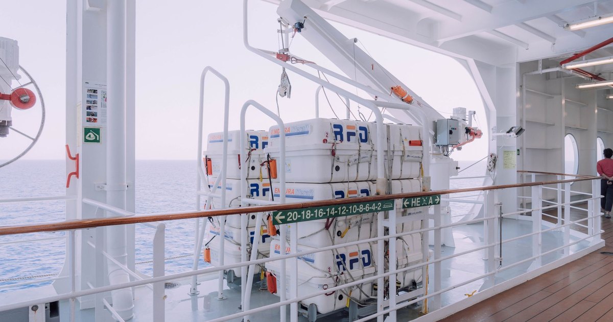 Cruise ship deck with lifeboats and safety equipment overlooking the serene ocean.