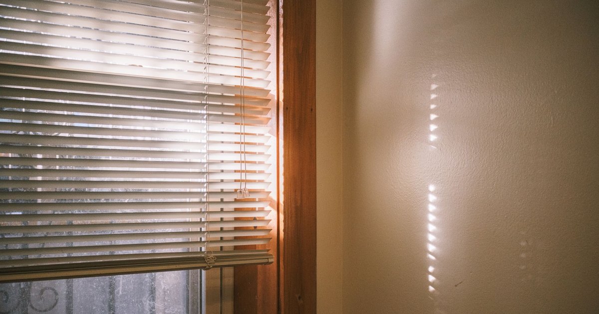 Warm sunlight casting shadows through window blinds, creating a tranquil indoor setting.