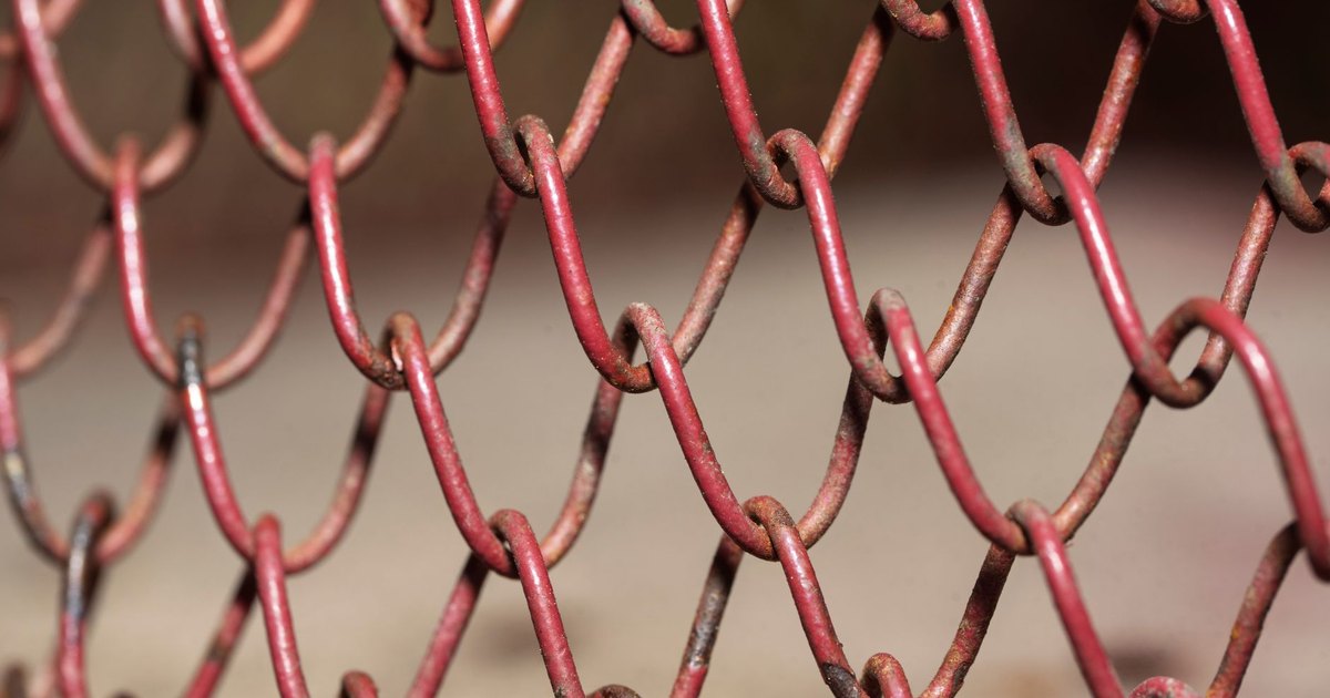 Detailed view of a red rusty chain link fence, highlighting texture and pattern.