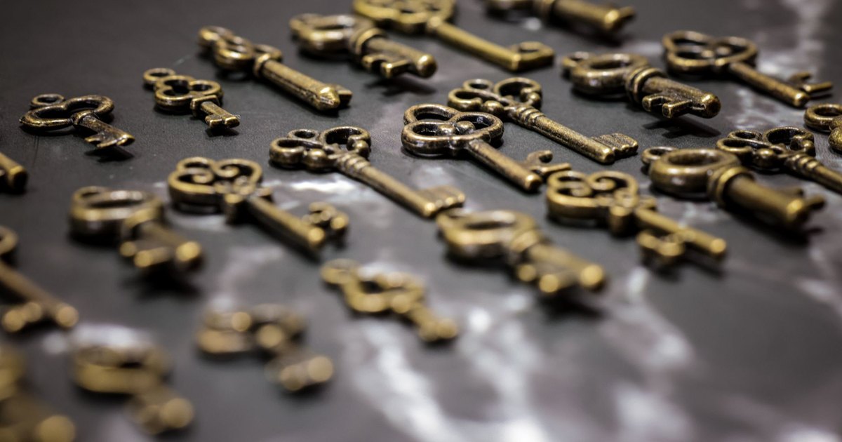A collection of vintage brass keys displayed in a scattered arrangement on a dark surface.
