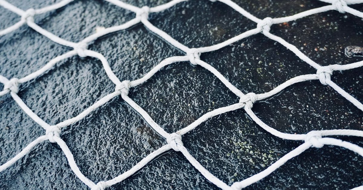 High-resolution close-up of white netting against a dark textured background, highlighting grid pattern.