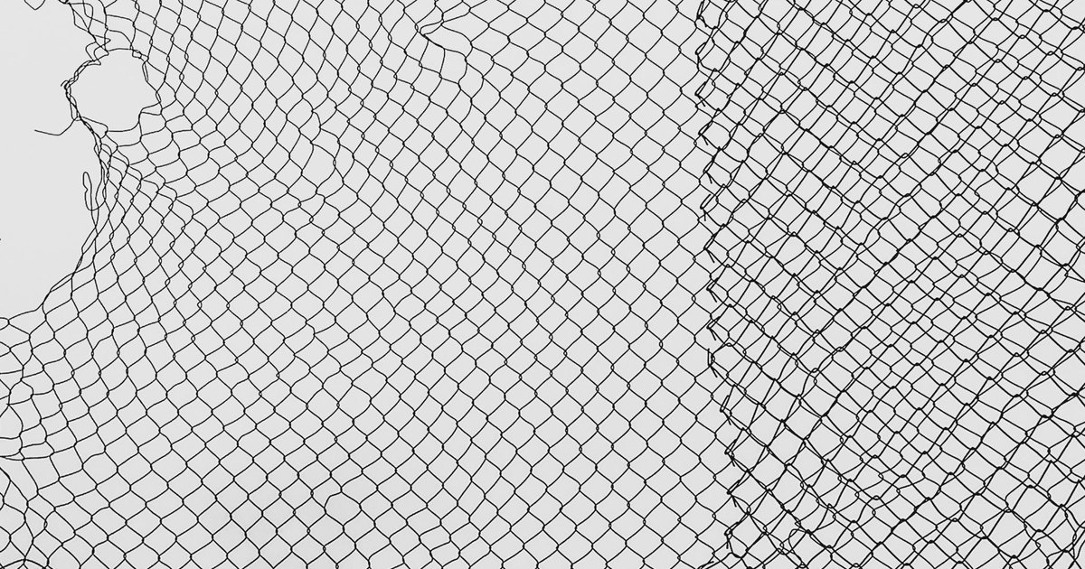 A close-up view of a torn, black safety net with intricate patterning against a white background.