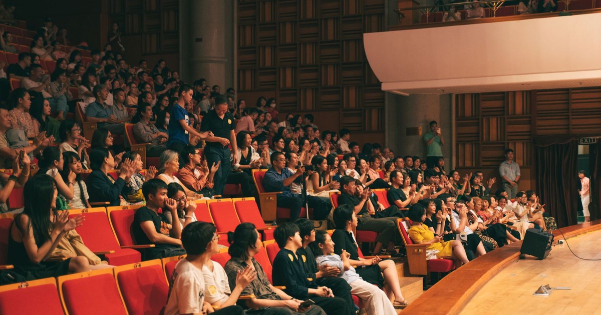 A lively audience applauding in a spacious concert hall, creating energy and excitement.