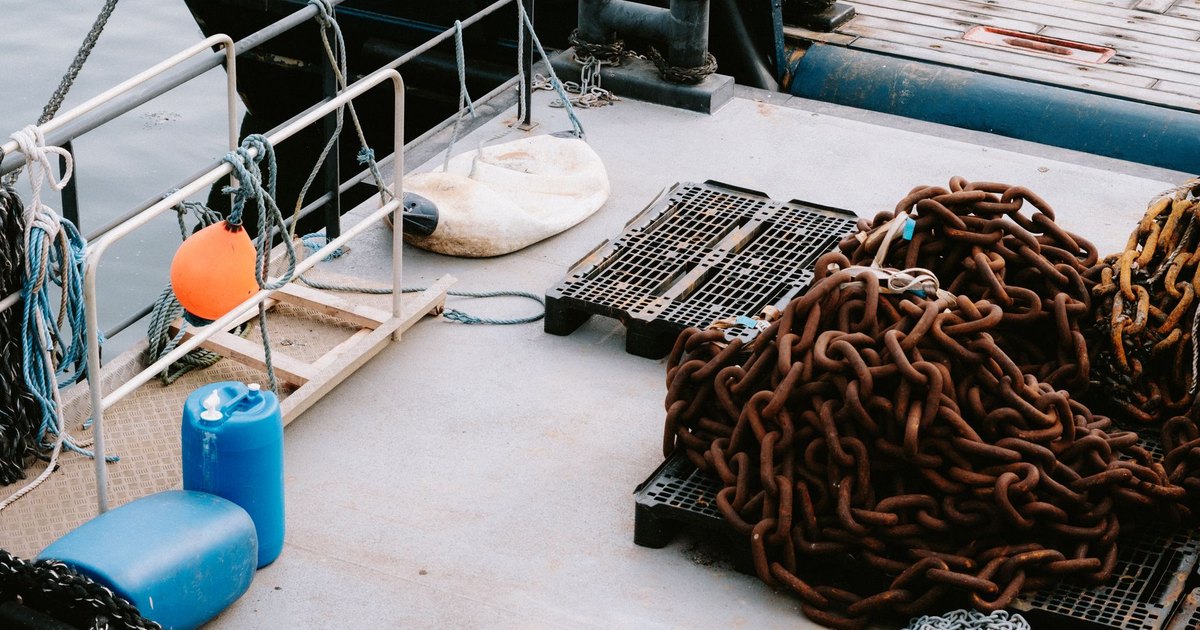 Close-up of rusty chains and nautical gear on a dock, highlighting maritime tools.