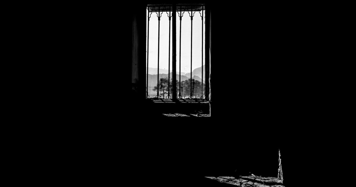 Monochrome shot of a window silhouette overlooking mountains, exuding a dramatic and moody atmosphere.