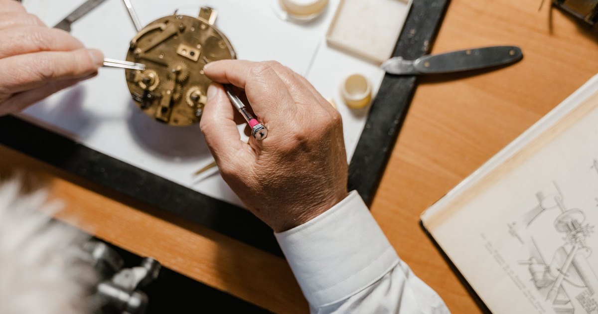 Detailed close-up of a watch repair process with tools and parts on a wooden table.