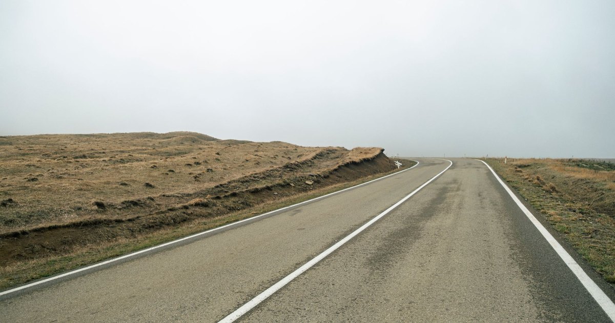 A solitary road traversing the barren Georgian landscape under a cloudy sky.
